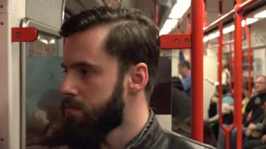 Metroyla seyahat eden yakışıklı bir hippi. Arka planda başkaları da var.