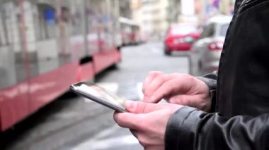 adam tablet üzerinde (yazarak) çalışır - şehir - geçen araba ve tramvay ile kentsel sokak - closeup