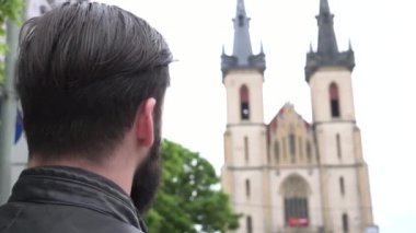 Genç yakışıklı hippi kiliseye bakar - şehir - arkadan vurulur