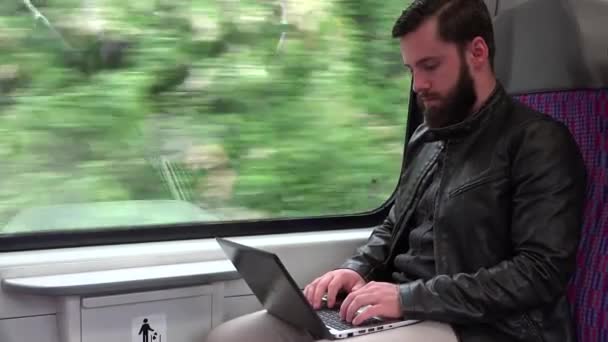 Молодой красивый хипстер путешествует на поезде и работает за компьютером (ноутбук) - город - крупный план — стоковое видео