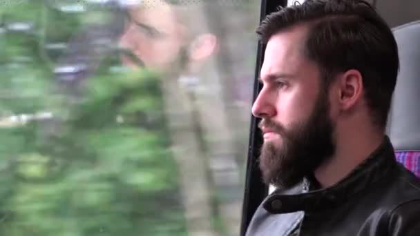 Молодой красивый хипстер путешествует на поезде и смотрит в окно - город - крупный план — стоковое видео
