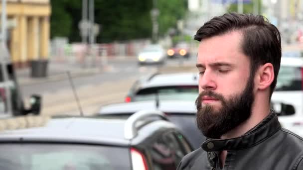 Joven hombre hipster guapo mira a su alrededor - ciudad - calle urbana con coches de paso - cara de primer plano — Vídeo de stock