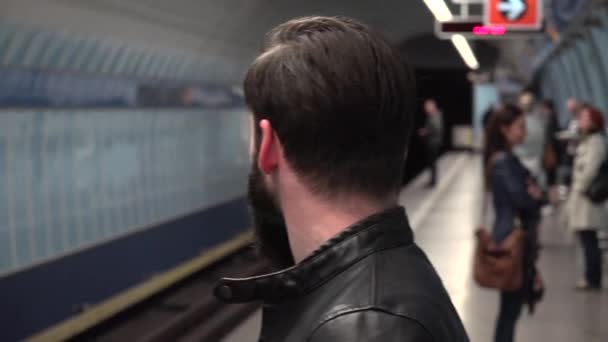 Giovane bello hipster uomo aspetta sulla metropolitana nella stazione della metropolitana - altre persone in background — Video Stock