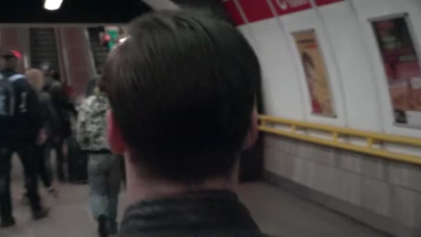 PRAGUE, CZECH REPUBLIC - MAY 2, 2015: young handsome hipster man walking in subway station (corridor) - other people in background - shot from back - shaky shot — Stock Video