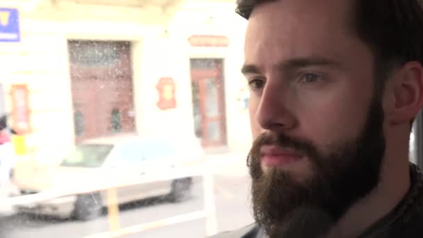 Jeune homme hipster beau voyage en tram et regarde par la fenêtre - rue avec des gens - gros plan — Video