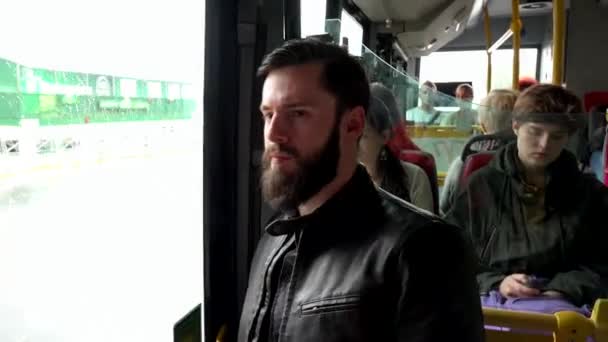 Πράγα, Τσεχική Δημοκρατία-30 Μαΐου, 2015: νέος όμορφος χίπστερ άνθρωπος ταξιδεύει με λεωφορείο με άλλους ανθρώπους στο παρασκήνιο-αστικός δρόμος στην πόλη — Αρχείο Βίντεο