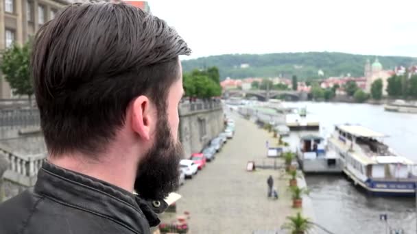 Jonge knappe hipster man kijkt vanaf de brug - rivier met boten - waterkant - schot van achteren — Stockvideo