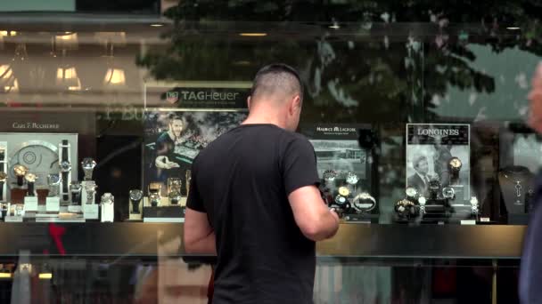 PRAGUE, RÉPUBLIQUE TCHÈQUE - 30 MAI 2015 : ville - magasin de montres (vitrine) - rue urbaine - promeneurs - l'homme regarde les montres — Video