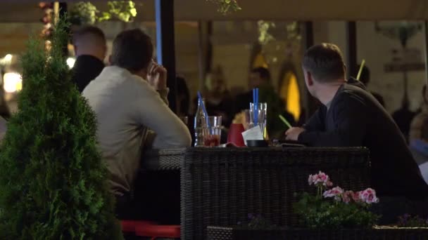 Prag, Tjeckien-30 maj 2015: två män sitter i en restaurang och pratar-urbana gata med promenader människor — Stockvideo