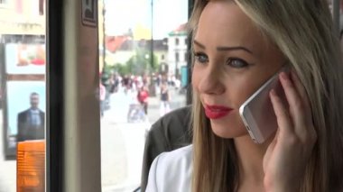 Tramvayla seyahat eden genç ve çekici sarışın kadın ve akıllı telefonlu telefon - yakın plan