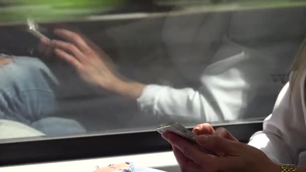 Fiatal vonzó szőke nő utazik vonattal és dolgozik okostelefon - közelkép - tükröződés az ablakban — Stock videók