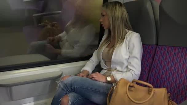 電車で旅をして窓から外を見る若い魅力的なブロンドの女性 — ストック動画