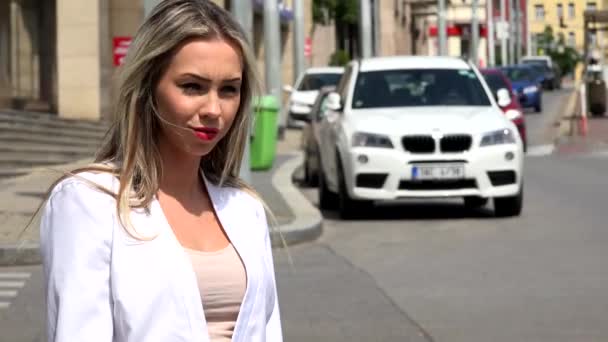 Young attractive blonde woman looks around - urban street in the city with cars — Stock Video