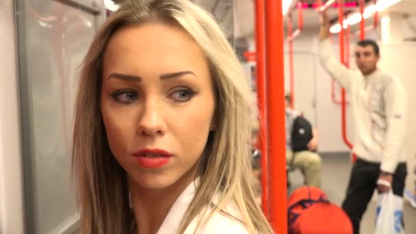 Young attractive blonde woman traveling by subway and looks around - other people in the background - closeup (detail) — Stock Video