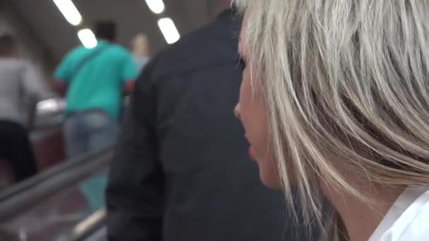 Junge attraktive blonde Frau fährt auf der Rolltreppe in der U-Bahn — Stockvideo