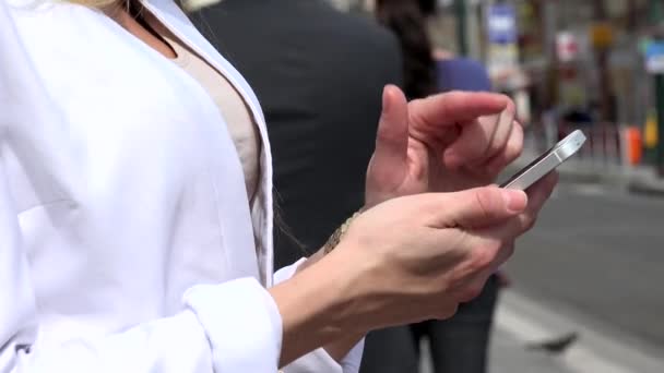 Молодая привлекательная блондинка работает на смартфоне - городской улице с трамваем и людей в городе - крупный план — стоковое видео