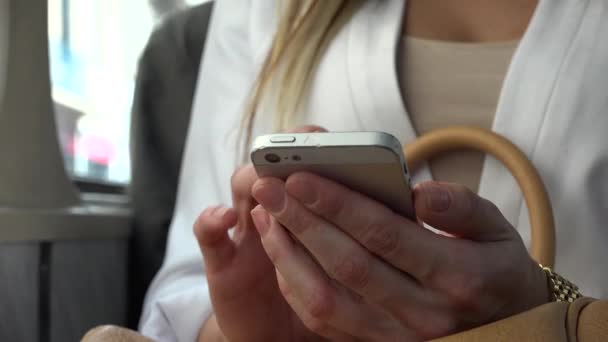 Jeune femme blonde attrayante voyageant en tram et travaille sur smartphone - gros plan — Video