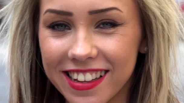 Jovem mulher loira atraente sorri para a câmera - rua urbana na cidade - close-up — Vídeo de Stock