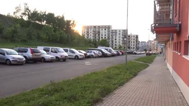 PRAGA, REPÚBLICA CHECA - 31 DE MAYO DE 2015: calle (coches aparcados) con edificio y naturaleza - puesta de sol en el fondo - steadicam — Vídeo de stock