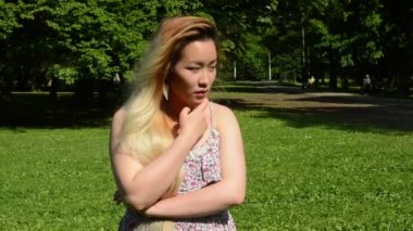 Genç ve çekici Asyalı kadın parktaki silahlarla düşünüyor.