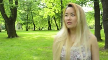 Genç Asyalı çekici tebessüm kadın parkta yürüyor - duygular - durağan