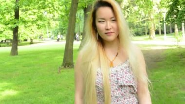 Genç Asyalı çekici gülümseyen kadın parkta yürüyor - yukarı bakıyor - istikrarlı