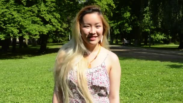Genç, çekici, mutlu Asyalı kadın parkta döner ve gülümser. Kameraya gülümser. — Stok video