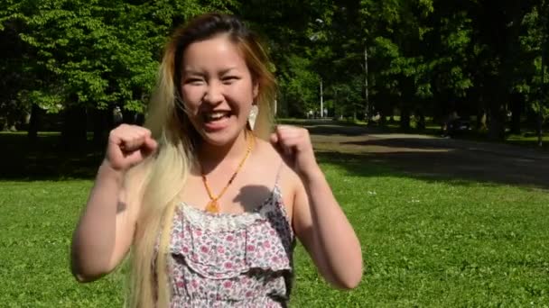 Joven atractivo feliz asiático mujer vueltas encima y sonrisas en el parque - sonrisas a cámara — Vídeos de Stock