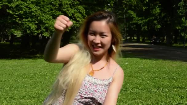 Young attractive asian woman plays that she rides imaginary car in the park — Stock Video