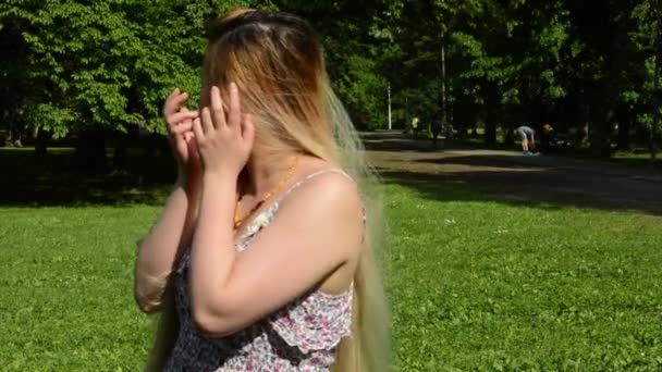 매력적 인 젊은 행복 한 동양 여성이 돌아서서 공원에서 미소를 지으며 카메라 앞에 미소를 짓는다 — 비디오