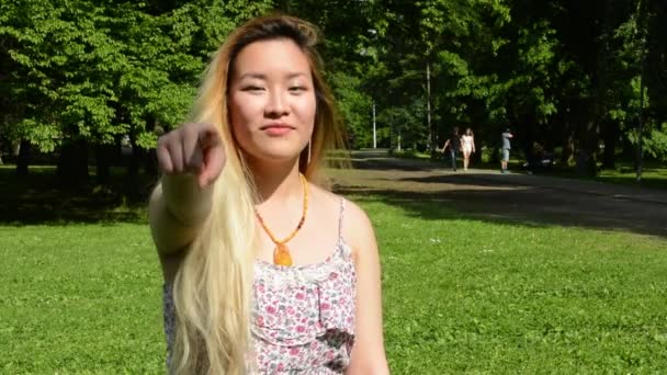 Joven atractivo asiático mujer muestra dedo adelante en el parque — Vídeo de stock