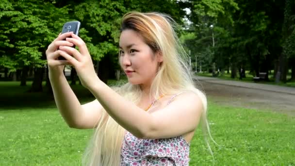 Joven atractivo feliz asiático mujer vueltas encima y sonrisas en el parque - sonrisas a cámara — Vídeos de Stock