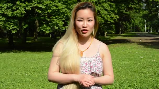 Jeune attrayant heureux asiatique femme parle à caméra et gesticule dans le parc — Video