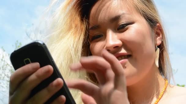 Joven atractivo feliz asiático mujer vueltas encima y sonrisas en el parque - sonrisas a cámara — Vídeos de Stock