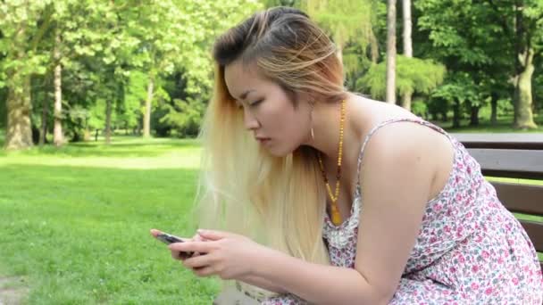 Joven atractivo feliz asiático mujer vueltas encima y sonrisas en el parque - sonrisas a cámara — Vídeos de Stock