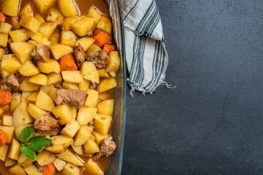 Sağlıklı yemek atıştırmalığı için masanın üstünde haşlanmış patates ve sebzeli gulaş porsiyonu. Arka planda metin yiyecekleri için fotokopi alanı.