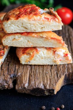 Kalın hamurlu hamur üzerine pizza fast food peyniri, domates sosu, domates ve diğer malzemeler. Masanın üzerinde sağlıklı yiyecek, açık hava atıştırmalığı. Arka plan metni için fotokopi alanı.