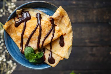 Beyaz tabakta krepler. İnce krepler. Çikolata şuruplu, düz pasta.