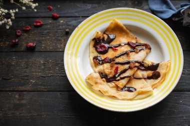 Beyaz tabakta krepler. İnce krepler. Çikolata şuruplu, düz pasta.