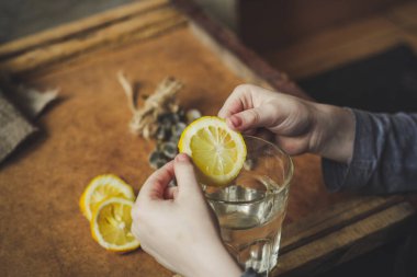 Birisi limon dilimini suyla bardağa koyuyor.