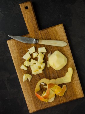 Kesme tahtasında siyah bir zeminde dilimlenmiş taze çiğ patates