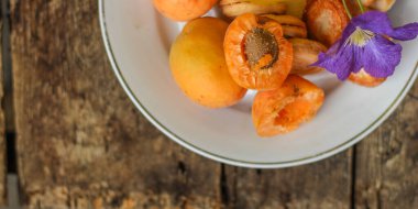 Tahta arka planda cam bir kasede taze kayısılar..