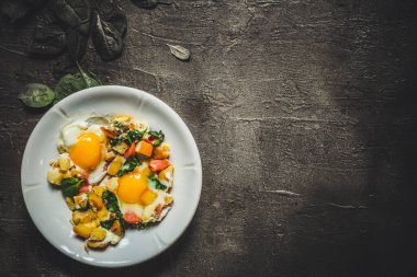 Ahşap arka planda sebzeli sahanda yumurta. en üstteki görünüm.