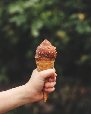 Çikolatalı dondurma külahı tutan kişi.