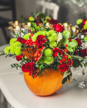 Servis masasında balkabağında çiçekler olan buket.