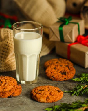 Kurabiye ve hediye kutularıyla bir bardak süt.