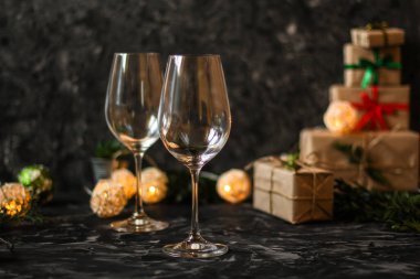 Noel arkaplanı, hediye kutuları ve karanlık bir masada gözlük..