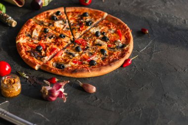 Siyah arka planda pepperonili pizza, domates, peynir, mantar ve zeytin. en üstteki görünüm.