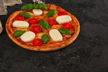 Siyah arka planda mozzarella, fesleğen ve sebzeli pizza. Yakın çekim görüntüsü. Boşluğu kopyala