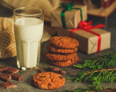 Kurabiye ve hediye kutularıyla bir bardak süt.